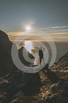 Man mountaineer tacking photography standing on rock of peak mountain at sunset. Ryten Mountain, Norway