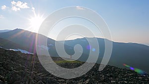 A man in the mountains photographs the landscape on his smartphone. A tourist with a backpack photographs the sunset on a mountain