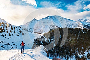 A man in the mountains. Ski touring on a split snowboard. A man stands with his back to the viewer and looks at the mountain