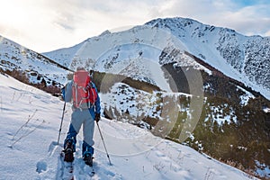 A man in the mountains. Ski touring on a split snowboard. A man stands with his back to the viewer and looks at the mountain