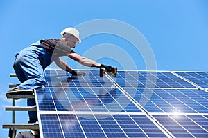 Man mounting modern solar batteries on house`s roof.