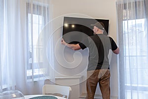 Man mounting new TV on the wall. Man installing television at home photo