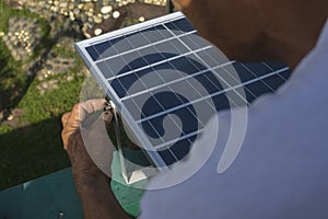 A man mounting a small 50 watt Polycrystalline solar panel on the eaves of a roof of a bungalow house