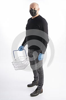 Man with mouth protection and hand gloves carrying a shopping basket, isolated on white background