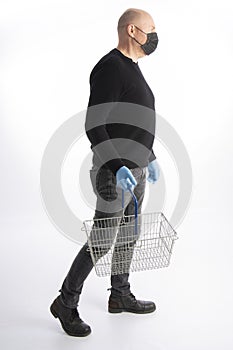 Man with mouth protection and hand gloves carrying a shopping basket, isolated on white background