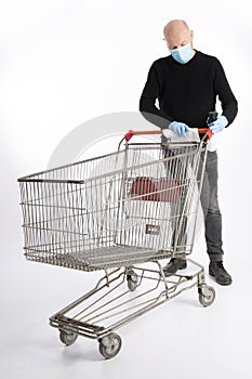 Man with mouth protection and hand gloves cleaning his shopping cart, isolated on white background