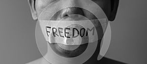 Man with mouth sealed in adhesive tape with Freedom message. Free of speech, freedom of press, Human rights, Protest dictatorship