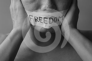 Man with mouth sealed in adhesive tape with Freedom message. Free of speech, freedom of press, Human rights, Protest dictatorship