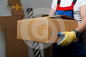 Man mover in uniform holding cardboard box, close up