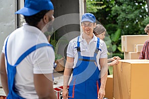 Man movers worker in blue uniform unloading cardboard boxes from truck.Professional delivery and moving service