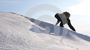 Man moves to the top to his success. Climber climbs snowy mountain in rays of bright sun. tourist makes climb to top on