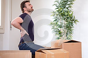 Man moving boxes and feeling back pain because heavy weight