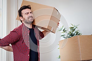 Man moving boxes and feeling back pain because heavy weight