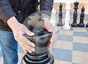 Man moving giant chess piece king outdoor