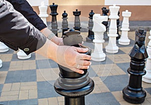 Man moving giant chess piece king outdoor