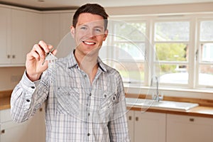 Man Moving Into New Home Holding Keys On House Shaped Keyring