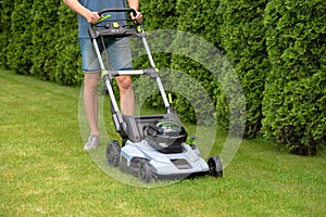 Man mowing grass with electric lawn mower in the backyard