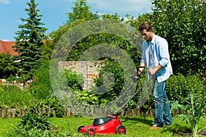 Man is mowing the lawn in summer