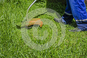 Lawn mower at work, a working man mows high grass cares for gozon. Grass-cutter closeup