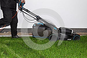 A man mows the grass with an electric mower with a cutting width of 44 centimeters and a power of 1800 watts.