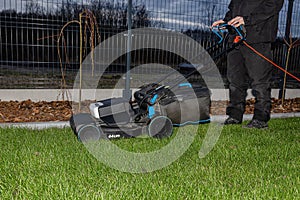 A man mows the grass with an electric mower with a cutting width of 44 centimeters and a power of 1800 watts.