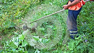 Man mows the grass with a manual petrol lawn mower in Slow Motion. Process of lawn trimming with a hand mower. Side view