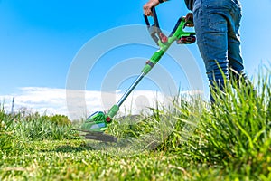 Man mows the grass in the meadow with a hand-held cordless lawnmower