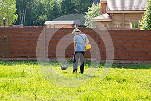 Man mows the grass with string trimmer