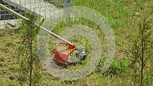 A man mows the grass in the summer on the field with a gasoline trimmer, background, close-up