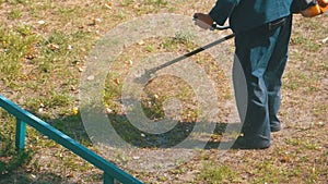 Man mows grass using a portable lawnmower