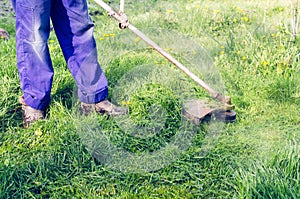 A man mows a green grass lawn mower on a sunny day