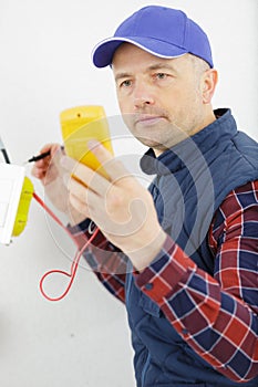 man with multimeter checking voltage in wall fixture