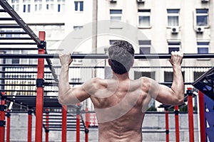 Man muscular back athlete doing pull ups with proper form, sport concept