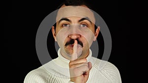 Man with mustache making silence, shushing gesture over black background