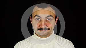 Man with mustache nods his head approvingly over black background