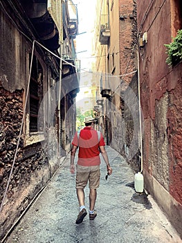 a man in a narrow alley, Italian holidays, an old narrow street in an Italian town, a man in a hat