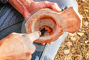 A man in nature carves a kuksa mug from wood. Handmade. Close-up