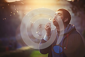 Man in nature. Harmony and romance. Dandelion blowing