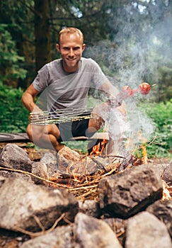 Man near campfire prepare vegetabels for grill