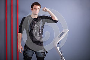 Man near EMS machine, muscle stimulation, showing biceps