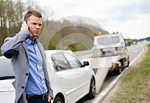 Man near his broken car on a roadside