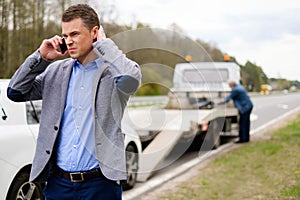 Man near his broken car on a roadside