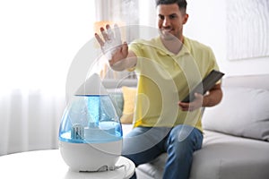 Man near modern air humidifier at home