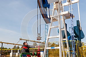 A man near the oil pump. Oil, gas industry. A man controls the process of the oil pump, the overall plan