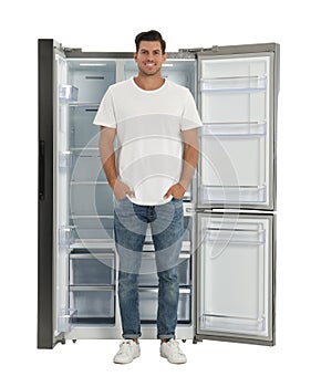 Man near open empty refrigerator on white
