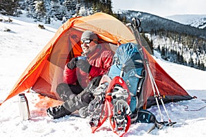 A man near a tent in the winter.