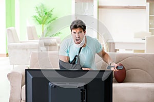 The man with neck and arm injury watching american football on tv