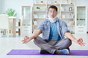 The man with neck injury meditating at home on floor
