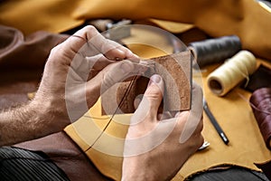 Man with needle sewing leather in workshop