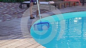 a man with a net for cleaning the pool collects garbage and insects.